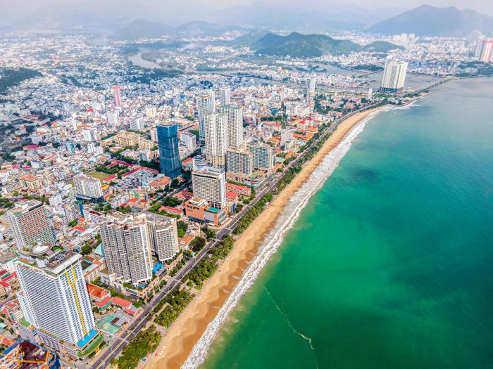 Nha Trang ảnh 1 - Bình minh trên bãi biển Nha Trang với mặt trời đỏ rực nhô lên từ biển khơi, ánh sáng vàng óng phủ lên những con sóng lăn tăn và hàng dừa nghiêng bóng.