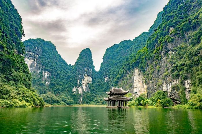 Tràng An - Ninh Bình ảnh 1 - Bức tranh thủy mặc với thuyền nan nhẹ trôi trên dòng sông xanh ngắt, xung quanh là những vách núi đá vôi sừng sững phủ đầy cây xanh.