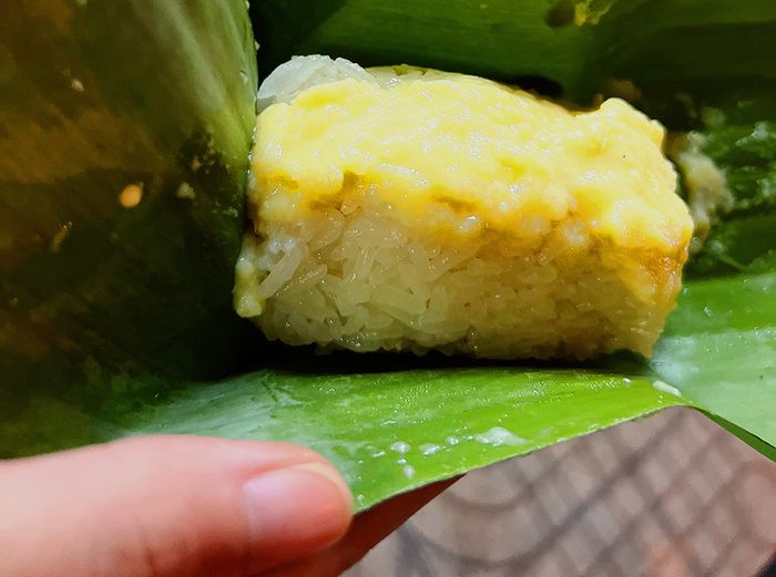 Xôi Cadé - Trần Phú ảnh 1 - Khoảnh khắc ẩm thực đầy hoài niệm, nơi những gói xôi xanh mướt được gói khéo trong lá chuối, bên trong là lớp xôi trắng ngần điểm xuyết cadé vàng tươi hấp dẫn.