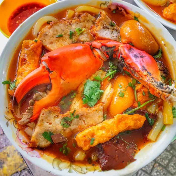 Ảnh 1: Tô bánh canh cua Cô Tư đầy ắp nguyên liệu với màu nước dùng đỏ nâu hấp dẫn