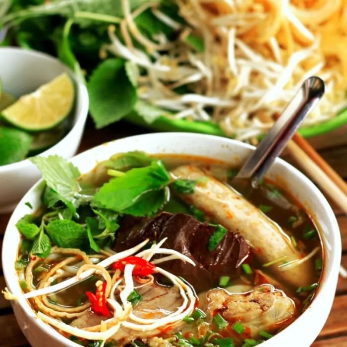 Hình ảnh tô bún bò Huế tại O Tú với nước dùng sóng sánh, thịt bò tái mướt cùng sắc xanh tươi của rau sống