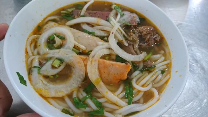 Hình ảnh tô bún bò Huế Cô Mai với nước dùng đỏ au, thịt bò tái mướt và rau sống xanh tươi