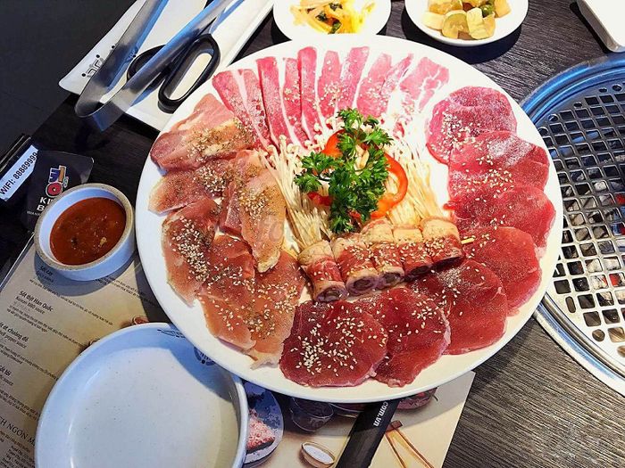 Bàn ăn đầy ắp thịt, hải sản nướng, đồ ăn phụ và nước ngọt có ga, kèm theo những cuộc trò chuyện vui vẻ với bạn bè và gia đình.