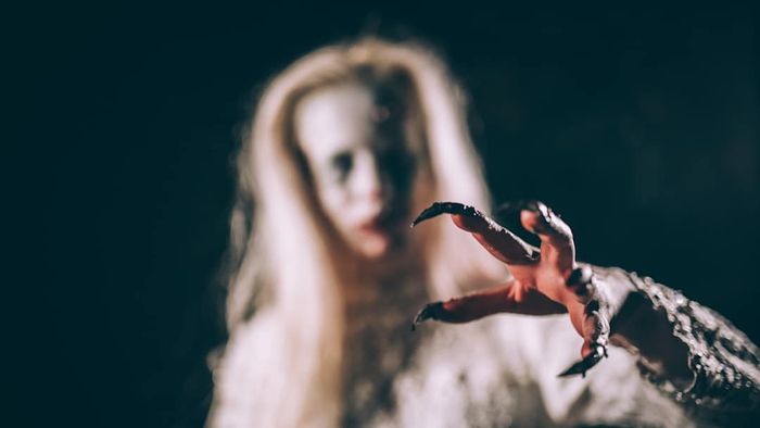 Woman out of focus with long nails in the foreground