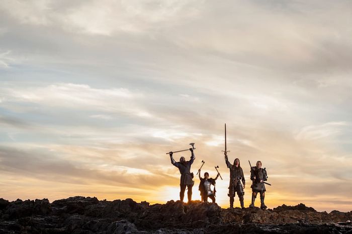 A wide-angle view of Vikings celebrating with weapons raised high.