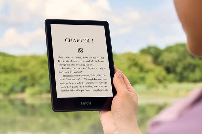 A person enjoying a Kindle Paperwhite e-reader outdoors