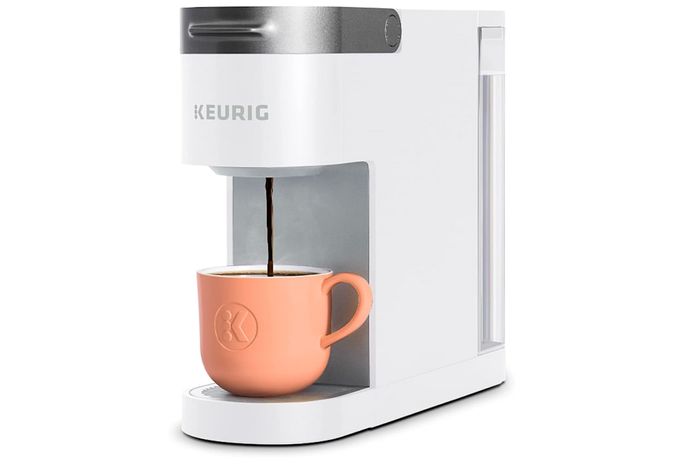 A Keurig K-Slim coffee maker on a white background, filling an orange cup with coffee.