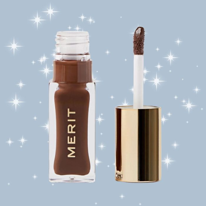 Merit lip gloss bottle and applicator, displayed against a sparkling background