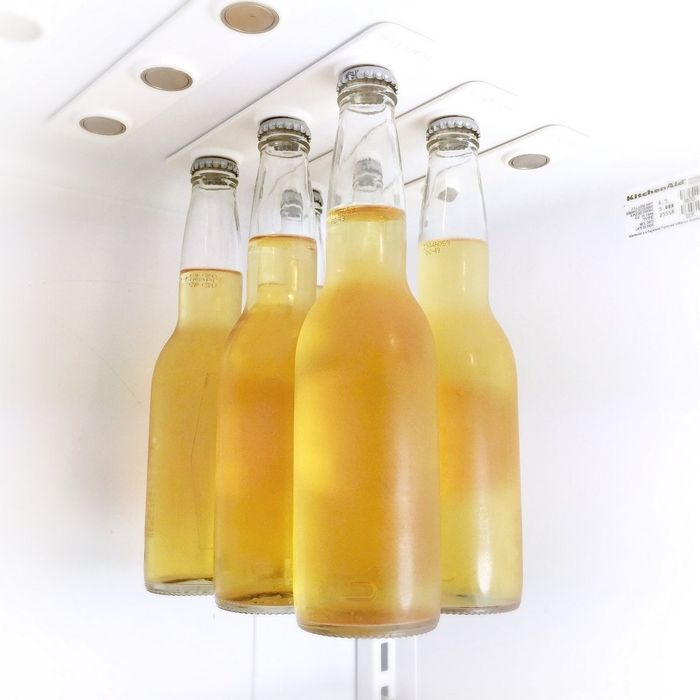 Six beers hanging from magnets on top of a fridge