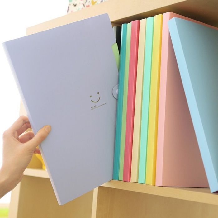 A purple accordion folder with a smiley face being pulled out from a bookshelf, ready for use.