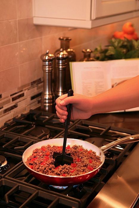 A close-up shot of a hand using the black nylon chopper to break up food.