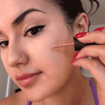 gif of Kayla gently dabbing blush on her cheeks with a brush applicator