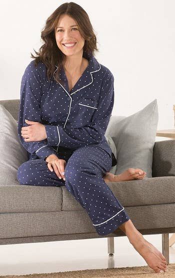 A model wearing the pajamas in blue, with white trim and tiny polka dots.