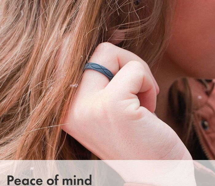 A hand wearing the band, which features a subtle two-wave pattern