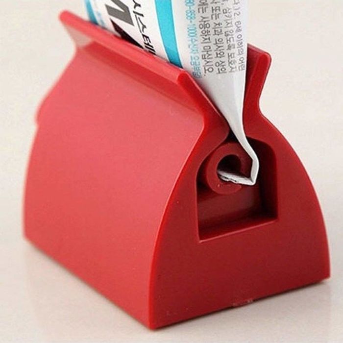 A close-up of the toothpaste tube being squeezed by the squeezer.
