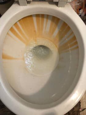 A toilet bowl with visible, unsightly rust stains.
