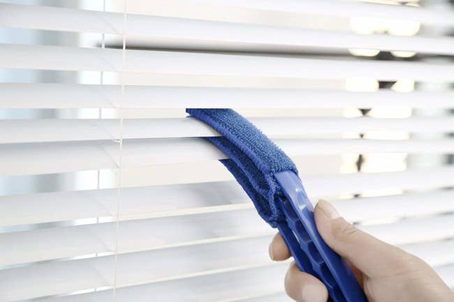 The wand simultaneously cleaning three sections of Venetian blinds.