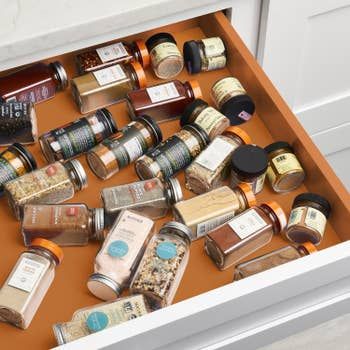 A drawer with spice bottles scattered on their sides, creating a chaotic mess.