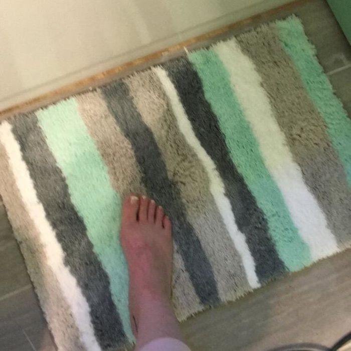 Reviewer stepping onto the bath mat with green stripes