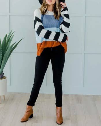 A model showcasing the pullover sweater featuring color-blocked design and black-and-white striped sleeves