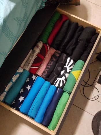 A reviewer's shirts folded neatly in a drawer, stacked sideways so all the designs are visible.