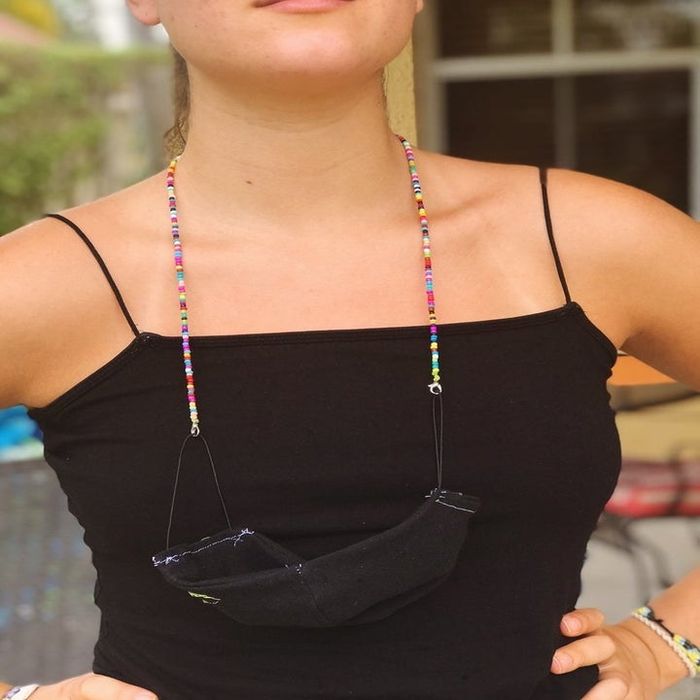 A model wearing a face mask as a necklace from the beaded chain