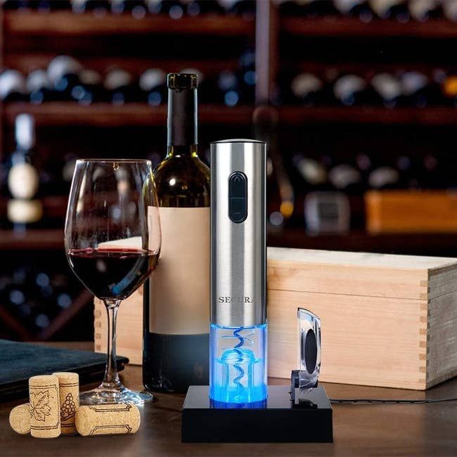 The sleek, tube-shaped metal wine opener placed beside a bottle of wine it has just uncorked.