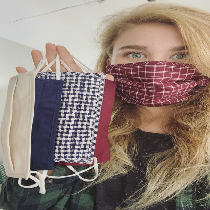 Mytour editor sporting a plaid mask while holding up four other masks in both solid colors and playful prints
