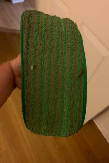 A used mop pad from a reviewer, looking heavily soiled and covered in dust.