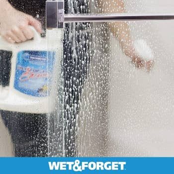 The cleaner being sprayed on a shower door.