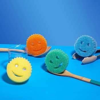 Four 1-inch thick round sponges with smiley faces, each with two eye holes and a crescent-shaped mouth hole