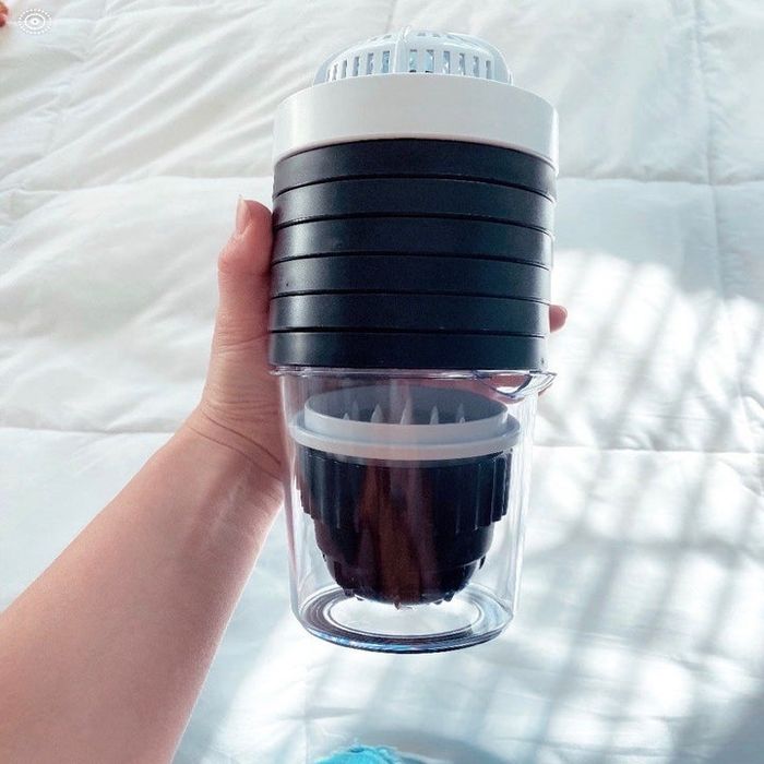 A Mytour editor holding a clear cup with eight black lids stacked on top.