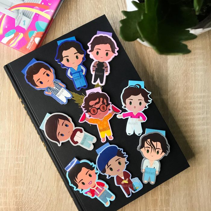 Bookmarks featuring cartoon-like depictions of Harry Styles in a variety of his iconic outfits