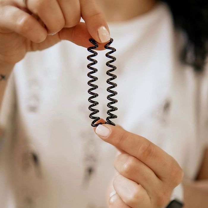 A model holding a brown spiraled hair tie between their fingers