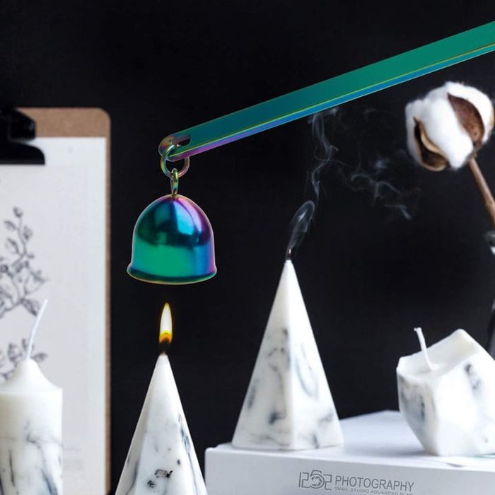 A rainbow-colored candle snuffer gently extinguishing a lit candle