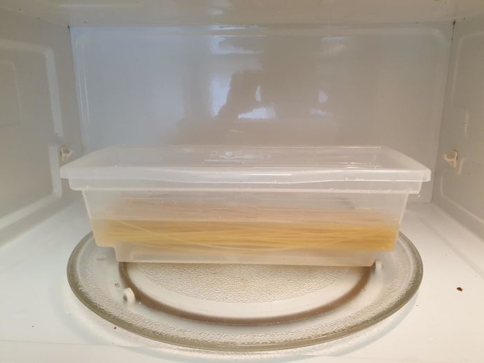 A reviewer's photo showing uncooked pasta and water inside the transparent, plastic microwave pasta cooker.