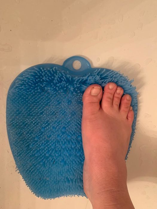 A reviewer demonstrating the foot massager and scrubber in use