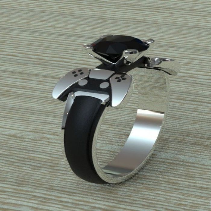 A sleek black and silver ring featuring a black stone surrounded by controller-shaped details