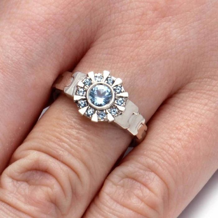 A hand modeling the ring, featuring the iconic arc reactor design from