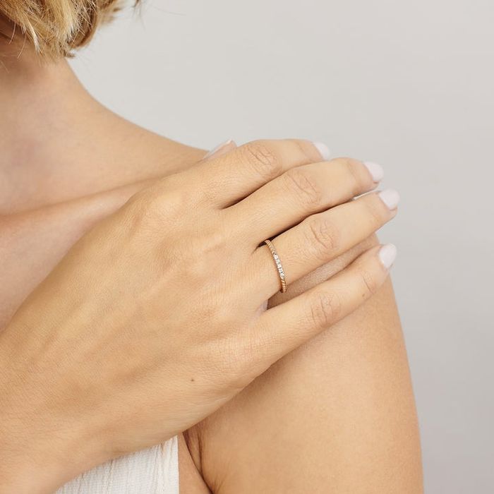 A model showcasing a slender gold band adorned with a chevron design and five sparkling diamonds