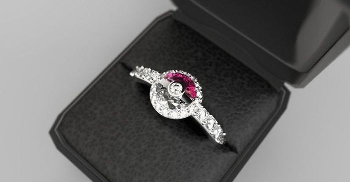 A ring displayed in a ring box, featuring a diamond-studded band and a red-and-white Poké Ball design at its center