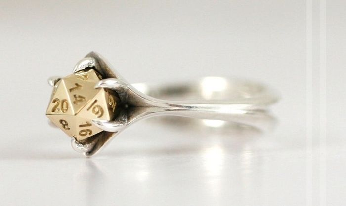 A silver band featuring a gold centerpiece designed to resemble a D20 dice