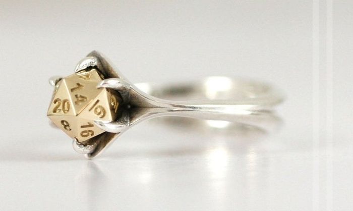 A silver band featuring a gold centerpiece designed to resemble a D20 dice