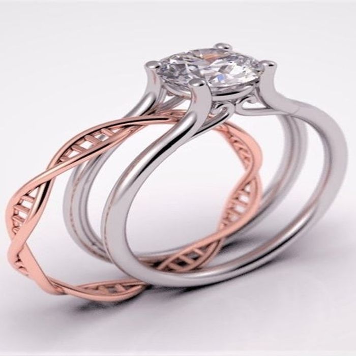 A sleek silver ring featuring a solitary diamond and a split band with a rose gold segment resembling a DNA strand partially embedded in the design