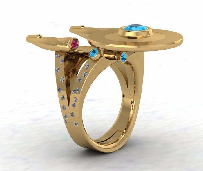 A gold ring featuring a diamond-studded band and a top designed to resemble the Starship Enterprise from 