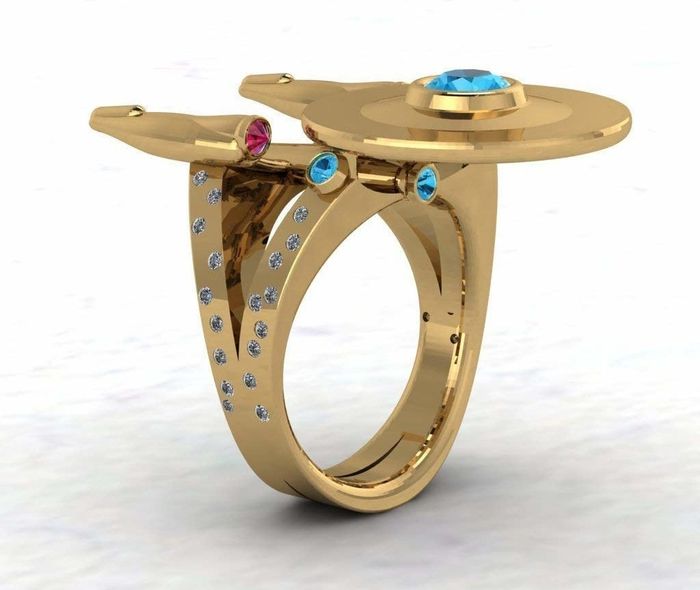 A gold ring featuring a diamond-studded band and a top designed to resemble the Starship Enterprise from