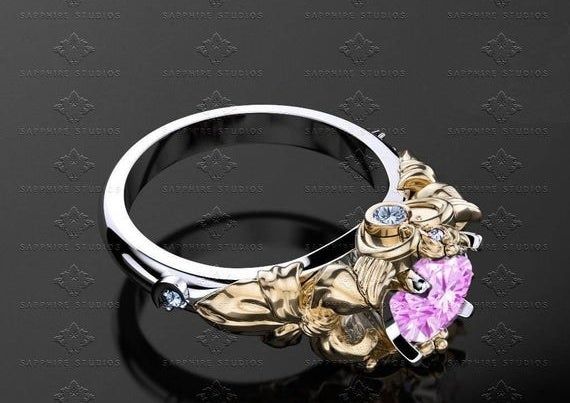 A sleek silver band adorned with a gold-etched setting and a stunning pink sapphire.