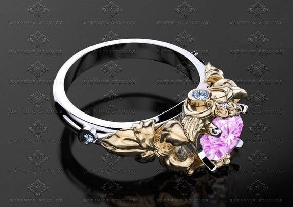 A sleek silver band adorned with a gold-etched setting and a stunning pink sapphire.