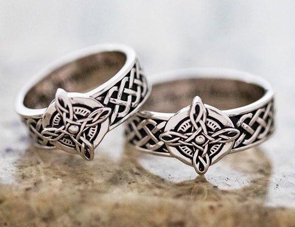 A set of coordinating silver rings featuring a detailed Celtic pattern on the band and center, complemented by an engraved interior.