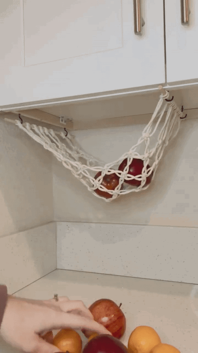 A gif showing a model placing apples and oranges into the hanging fruit basket